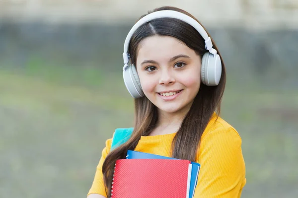 新しい音楽をチェックしてください。幸せな子供は屋外で音楽を聞く。ヘッドフォンの小さな子供は印刷された音楽を保持します。音楽学校と教育。新しい技術だ。現代の生活。重要な音楽的知識 — ストック写真