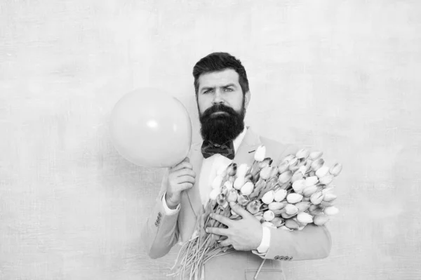 Aanwezig voor de echtgenoot. Een man met luchtballon. Verjaardagsfeestje. Baard man hipster met bloemenboeket. 8 maart. Bloemen voor vrouwen dag. Een man met baard en tulpen. Voorjaarsstemming. Liefdesafspraakje. Cadeauboeket — Stockfoto