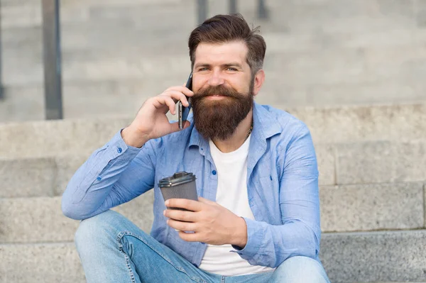 Una pequeña charla con alguien. Feliz hipster beber café hablando por teléfono al aire libre. Haciendo una llamada. Conexión de celular. Nueva tecnología. La vida moderna. El teléfono móvil facilita la comunicación — Foto de Stock