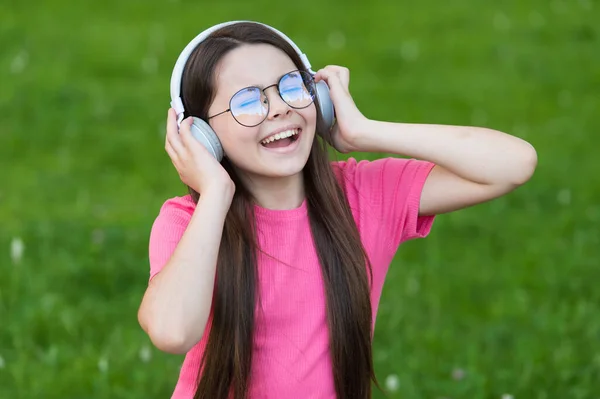 歌を通して幸せを追加します。幸せな歌手緑の芝生の上で歌を歌う。小さな女の子はヘッドフォンで歌うことを楽しむ。歌声だ。声楽の練習。夏の音楽。独唱を楽しむ — ストック写真