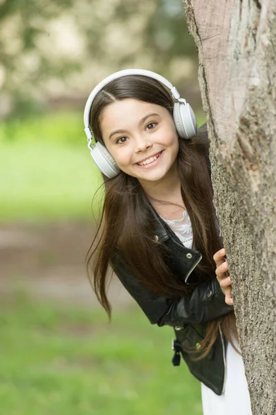 Baby tech. Happy child wear headphones outdoors. Small girl listen to music in headphones. Protecting hearing. Noise cancelling headphones. New technology. Headphones your child will appreciate