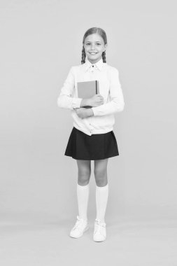 Gelecek için sağlam bir bilgi tabanı. Sarı arka plan üzerine kitap tutan sevimli küçük bir kız. Elinde kitap bilgisi olan sevimli küçük bir çocuk. Bilgi ve beceriler. Bilgi günü veya 1 Eylül