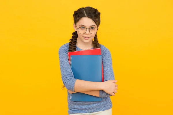 Logra tus objetivos de estudio. Niña pequeña sostiene libros de fondo amarillo. Niña de vuelta a la escuela. Estudio y educación. Estudio en casa y escolaridad. Enseñanza privada. Material de estudio para las clases escolares — Foto de Stock