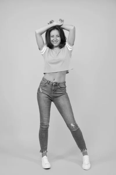 Beleza e fazer as pazes. Calça jeans Skinny combina com ela. A auto-confiança é a melhor roupa. Menina sexy fundo amarelo. Rapariga sexy. Menina sensual em estilo casual. Menina bonita com cabelo comprido. Moda e estilo — Fotografia de Stock