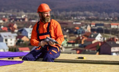 Çatı tamircisi. Çatıda adam var. Malzeme gereksinimleri. Çatının yalıtım yüzeyine kısmen üst üste binen malzeme katmanları yükle. Ana onarım çatısı. Düz çatı kurulumu