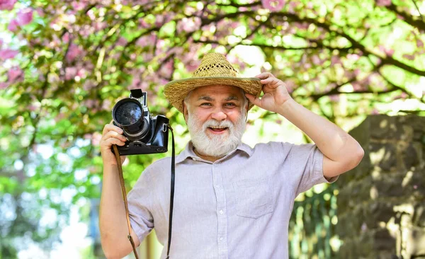 Férias. Foto de viagem. Fotógrafo no jardim florescente. Desfrutando de tempo livre. Viagens e turismo. Capturar a beleza. Avô feliz. Senior man hold câmera profissional. Viagens de reforma — Fotografia de Stock