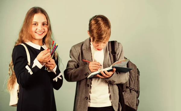 Il a besoin d'aide pour ses devoirs. Les petits enfants font leurs devoirs. Petit garçon et petite fille tiennent des stylos et un journal de devoirs. Club de devoirs scolaires. Éducation et études — Photo