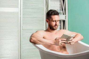 Maço banyoda kitaptan zevk alıyor. Tuvalette kitap okuyan seksi bir adam. Küvette çıplak maço. Seks ve rahatlama konsepti. Adamın kaslı bir vücudu var. Köpüğü dikkatlice suyla yıka. Kitap aşığı. Gerçek mutluluk.