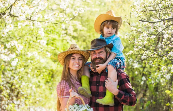 Lovely family outdoors nature background. Ranch concept. Happy family day. Mother father and cute son. Family farm. Farmers in blooming garden. Parents growing little baby. Spend time together — Stock Photo, Image