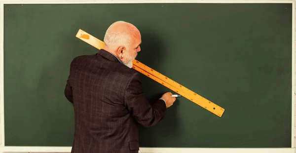線を引くひげを生やした家庭教師の男が黒板に定規で描く。学校に戻って学校の規律教育と知識。高校時代の幾何学的な形です先輩先生は絵を描きながら定規を使い — ストック写真