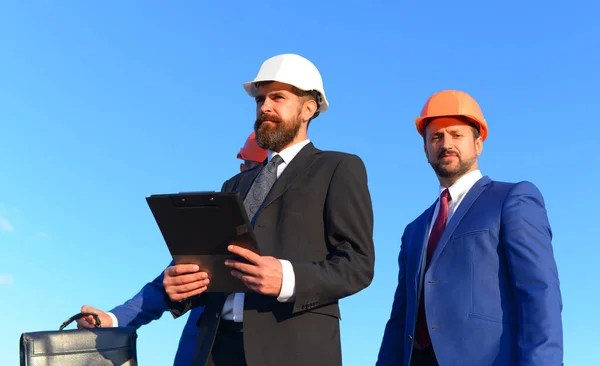 Les ingénieurs inspectent le chantier sur fond bleu. Les constructeurs travaillent ensemble — Photo