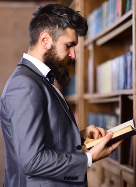 Klasik bir iç mimarisi olan, iyi giyimli yakışıklı bir adam kitap okuyor..