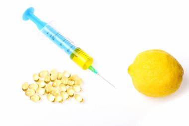 Beyaz arka planda izole edilmiş şırınga, kapsül ve taze limon..