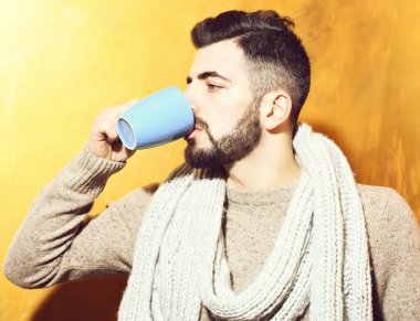 Sakallı adam çay içiyor, fincandan kahve içiyor.