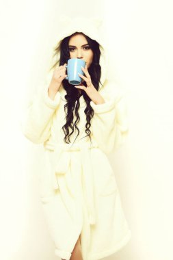 Fincanlı bej kadife bornozla poz veren seksi kız.