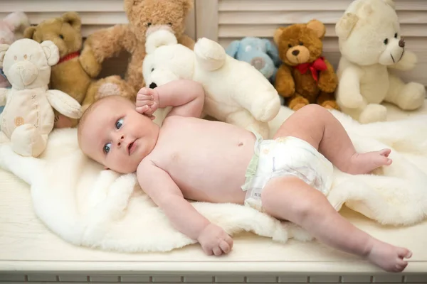 Bebé acostado en un edredón blanco. Bebé con ojos azules y curiosos — Foto de Stock