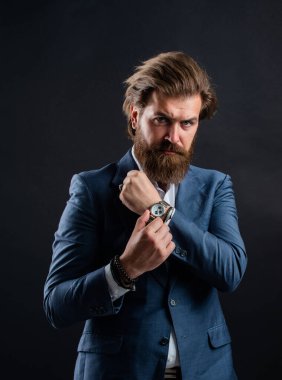 Erkek aksesuar. Ciddi sakallı iş adamı. Modern görünümlü şık, olgun bir adam. Erkek ofisindeki gardırop. Modaya uygun bir adam el saati takar. Resmi manken. Gri arka plandaki yakışıklı adam.