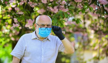 Yaşlı insanlar covid-19 'dan dolayı yüksek risk altındalar. Enfeksiyonun yayılma riskini sınırla. Dışarıda maskeli ve eldivenli kıdemli bir adam var. Enfeksiyon havada. Virüs enfeksiyonundan koru. Salgın konsepti