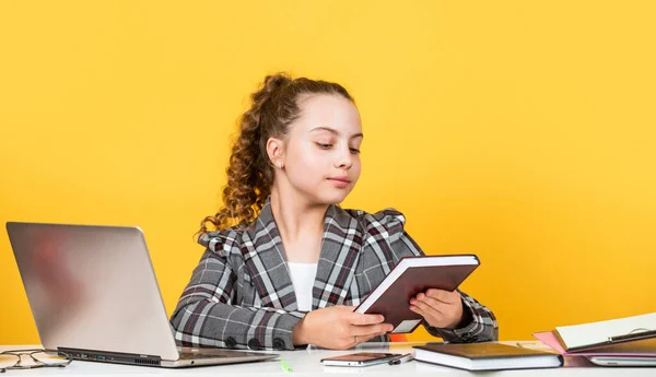 lets read book. schoolgirl has online homework. back to school. time to study. small girl in office. little businesswoman. happy childhood. kid with curly hair wear jacket. work on laptop