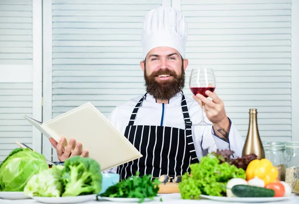 Exquisito concepto de cena. Degustación de vino. Coincidir con el vino y la comida como experto. El hombre usa sombrero y delantal disfrutan de la bebida gustativa. El chef maestro tiene una copa de vino. Añade un poco de alcohol. Qué vino sirven con la cena — Foto de Stock