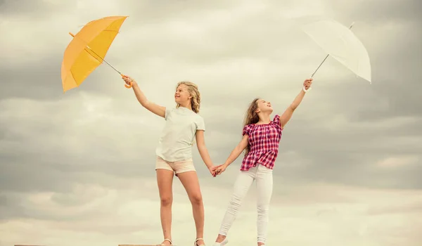 Il tempo cambia. Ragazze amiche con ombrelli cielo nuvoloso sfondo. Pronti per qualsiasi tempo. Vento o piovoso siamo preparati. Bambini spensierati all'aperto. Libertà e freschezza. Previsioni meteo — Foto Stock