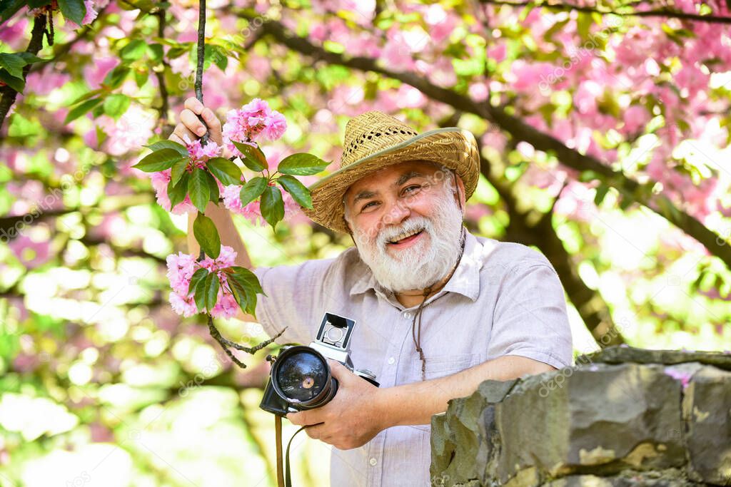 Retirement travel. Enjoying free time. Travel and tourism. Capturing beauty. Happy grandfather. Spring holidays. Travel photo. Photographer in blooming garden. Senior man hold professional camera