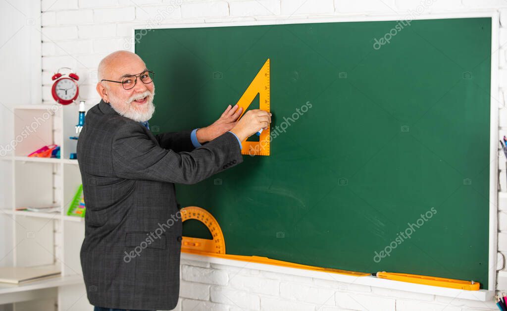 tutor man in glasses draw with triangle on blackboard. back to school. what angle you look. geometric shapes. high school modern education. senior man teacher use triagle while drawing
