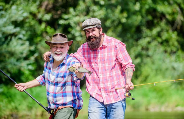 Pesca de caza mayor. amistad. turismo de caza. padre e hijo pescando. dos pescador feliz con caña de pescar y red. Acampar en la orilla del lago. concepto de una escapada rural. hobby. Tiempo de pesca con mosca — Foto de Stock