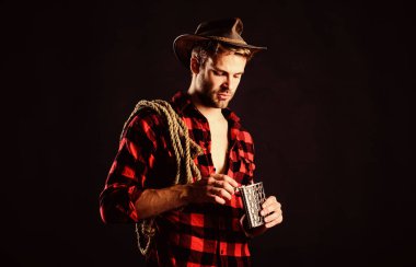 Kovboy içkisi. Çiftlikte kareli gömlek. Vahşi batı rodeosu. Siyah şapkalı adam. Kement ipli bir kovboy. Batı. Klasik tarz adam. Vahşi Batı eski kovboy. Batı kovboy portresi