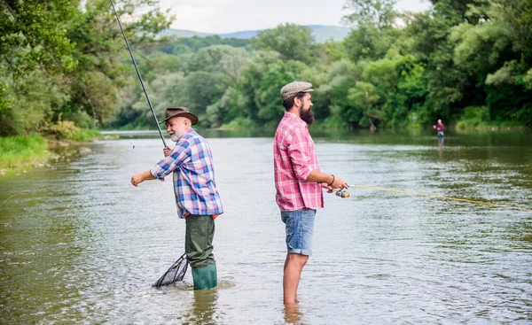 Chiama Hobby. hobby e attività sportive. Esche di trota. amicizia maschile. legame di famiglia. due pescatori felici con canna da pesca e rete. weekend estivo. uomini maturi pescatore. padre e figlio pesca — Foto Stock