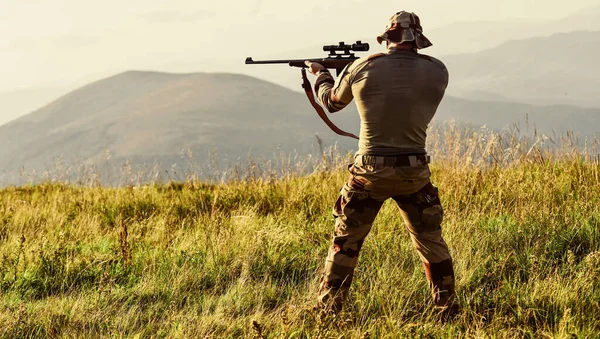 Frumoasă lovitură. Forţele armate. Haine militare cu arme. Războinic brutal. Puşcă pentru vânătoare. Hunter ţine puşca. Hunter munte peisaj fundal. Focus și concentrare vânător experimentat — Fotografie, imagine de stoc