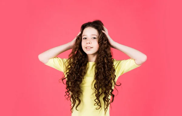 Menina pequena com cabelo encaracolado longo. moda modelo miúdo tem penteado morena. cabeleireiro para criança. shampoo cosmético para o cabelo. feliz dia das crianças. pouca beleza com aparência elegante — Fotografia de Stock