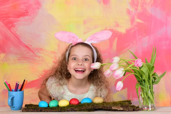 Glad påsk flicka i kanin öron med pennor, ägg, blommor — Stockfoto