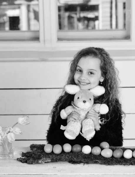 Щаслива дівчина з іграшкою кролика, квітами тюльпанів, великодніми яйцями — стокове фото