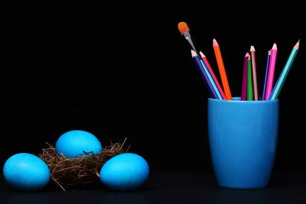 Ovos azuis tradicionais em ninho e caneca com lápis e escova — Fotografia de Stock