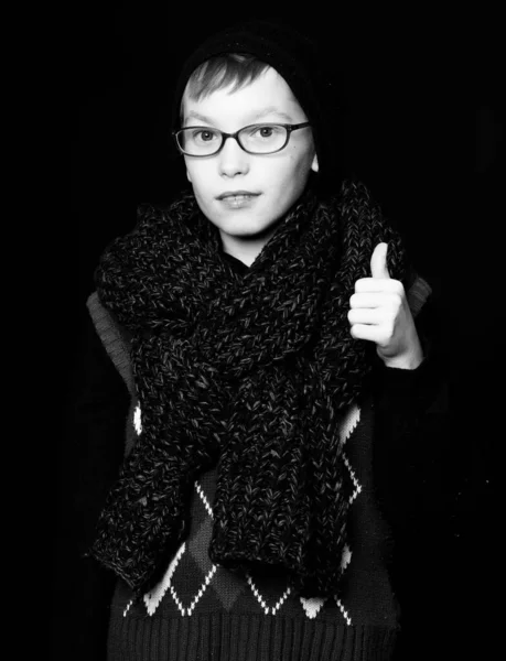 Pequeño chico nerd en gafas en negro fondo, sostiene el pulgar hacia arriba — Foto de Stock