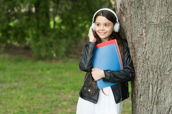 E-learning courses. Happy child listen to headphones. Small girl study online outdoors. E-learning. Music lesson. Distance education. E-learning activities. E-learning available from anywhere