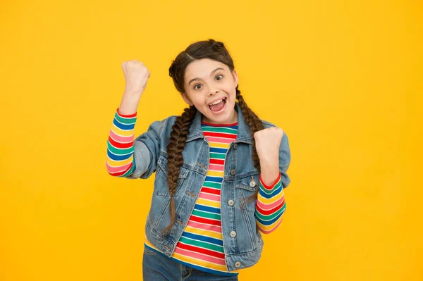 Πάντα νικητής. Χαρούμενη μικρή νικήτρια κίτρινο φόντο. Μικρό κορίτσι κάνει χειρονομία νικητής. Γιορτάζοντας τη νίκη ή την επιτυχία. Σούπερ κουλ. Ομορφιά. Απλή μόδα. Μοντέρνο στυλ. Φαίνεσαι νικητής. — Φωτογραφία Αρχείου