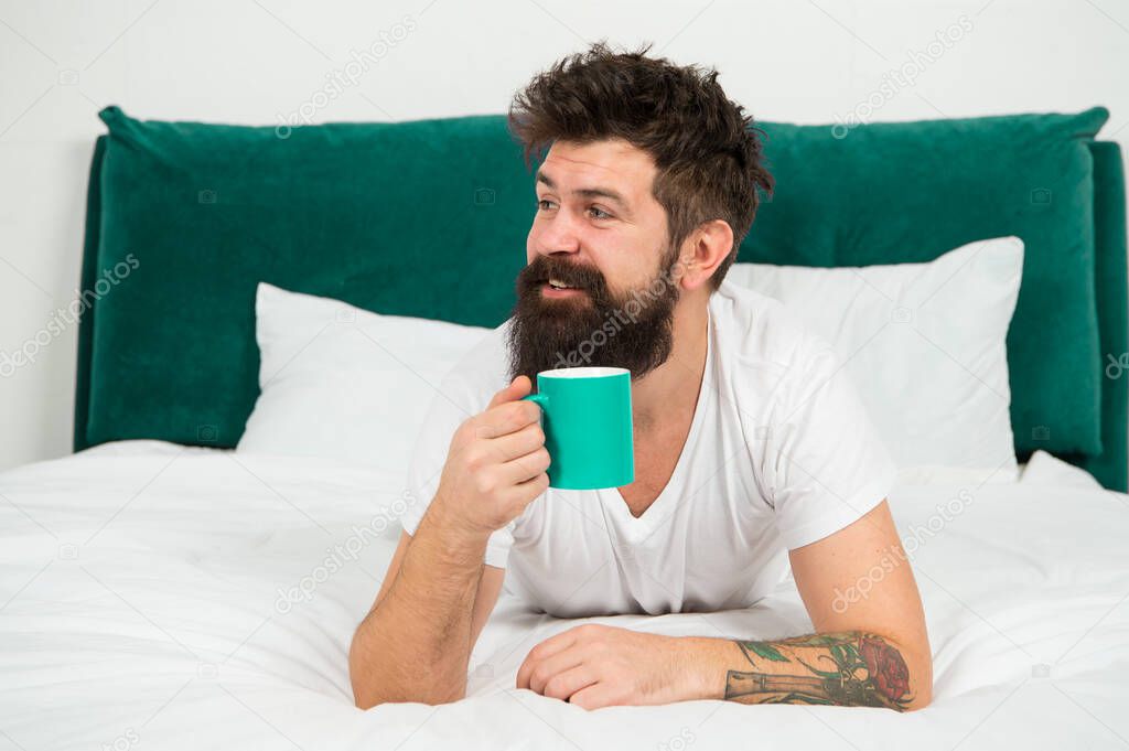 Morning mood. Bearded man drink morning coffee in bed. Hipster enjoy hot drink in morning. Breakfast tea. First thing in the morning