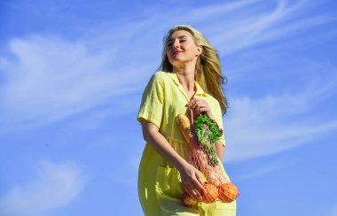 Bilinçli tüketim. Çevre trendi. Tekrar kullanılabilir çanta. Sağlıklı yiyecekler. Sıfır atık. Elbiseli kız çanta alışverişi yapıyor. Market poşeti. Yeniden kullanılabilir eko çanta. Elinde meyve dolu bir torba tutan kadın.