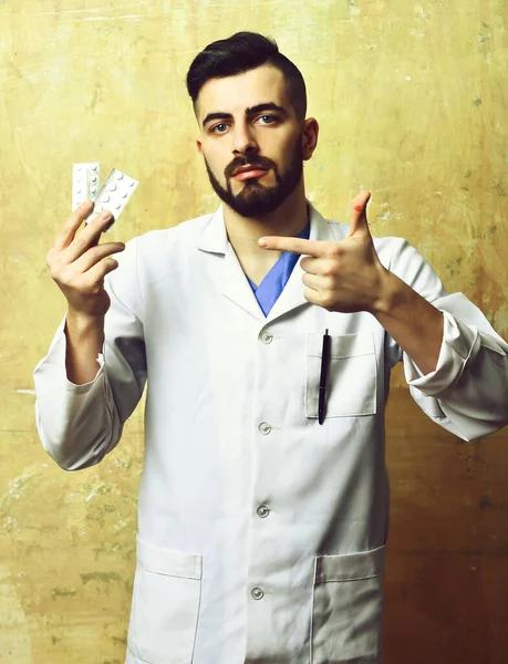 Doutor com barba e rosto seguro expressão apontando pílulas — Fotografia de Stock