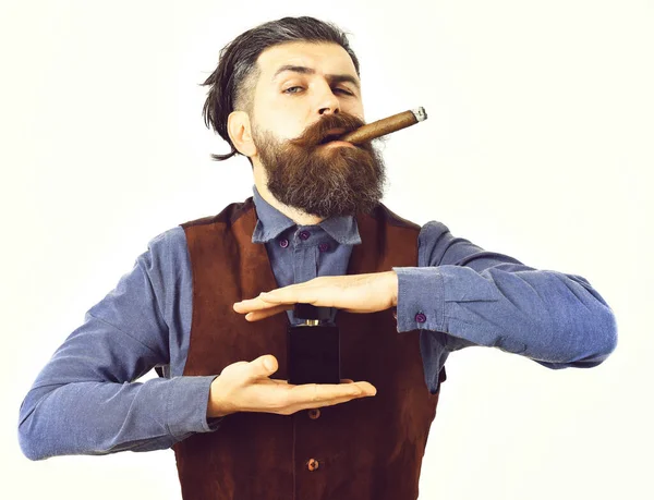 Bearded man smoking cigar with serious face, holding perfume — Stock Photo, Image