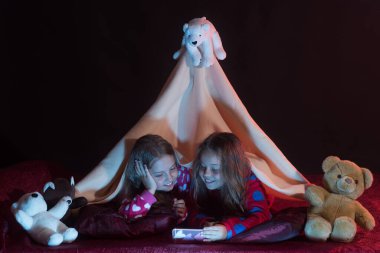 Çocuklar oyuncak ayılarla pijama partisi yaparlar. Gülümseyen kızlar