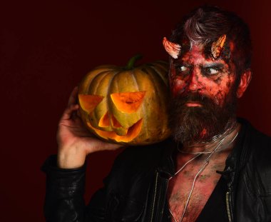 Boynuzlu ve ürkek bakışlı şeytan Jack O Fener 'i tutuyor