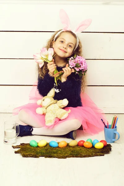 Chica feliz con juguete de conejo de Pascua, lápiz, flores de tulipán, huevos — Foto de Stock