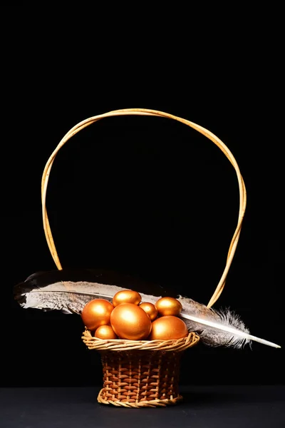 Huevos pintados en color dorado dentro de la cesta con pluma —  Fotos de Stock