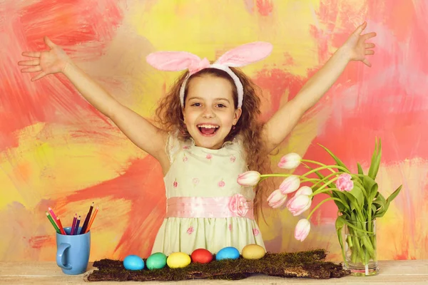 Счастливая пасхальная девушка в кроличьи уши с карандашами, яйцами, цветами — стоковое фото