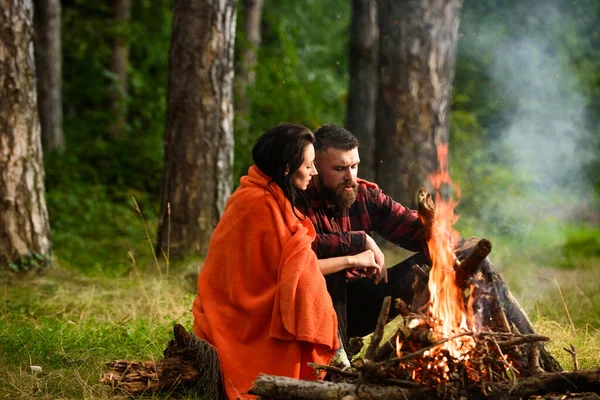 Man with woman hugs and warm near bonfire.