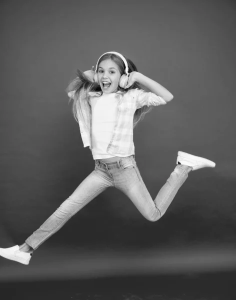 Skákání ve vzduchu. Snadná poslech hudby. Malá holka poslouchá hudbu ve sluchátkách. Tančící dívka. Šťastná holčička tancuje. Roztomilé dítě si užívá šťastnou taneční hudbu. Hudba je pro ni štěstí. — Stock fotografie