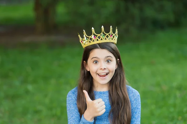 El mejor jefe de todos. Niño feliz en corona dar pulgares hacia arriba. Pequeño jefe sobre hierba verde. Reina de belleza. Fiesta de graduación. Gran concepto de jefe. Gloria y triunfo. Accesorio de moda de lujo. Actúa como dama piensa como jefa — Foto de Stock